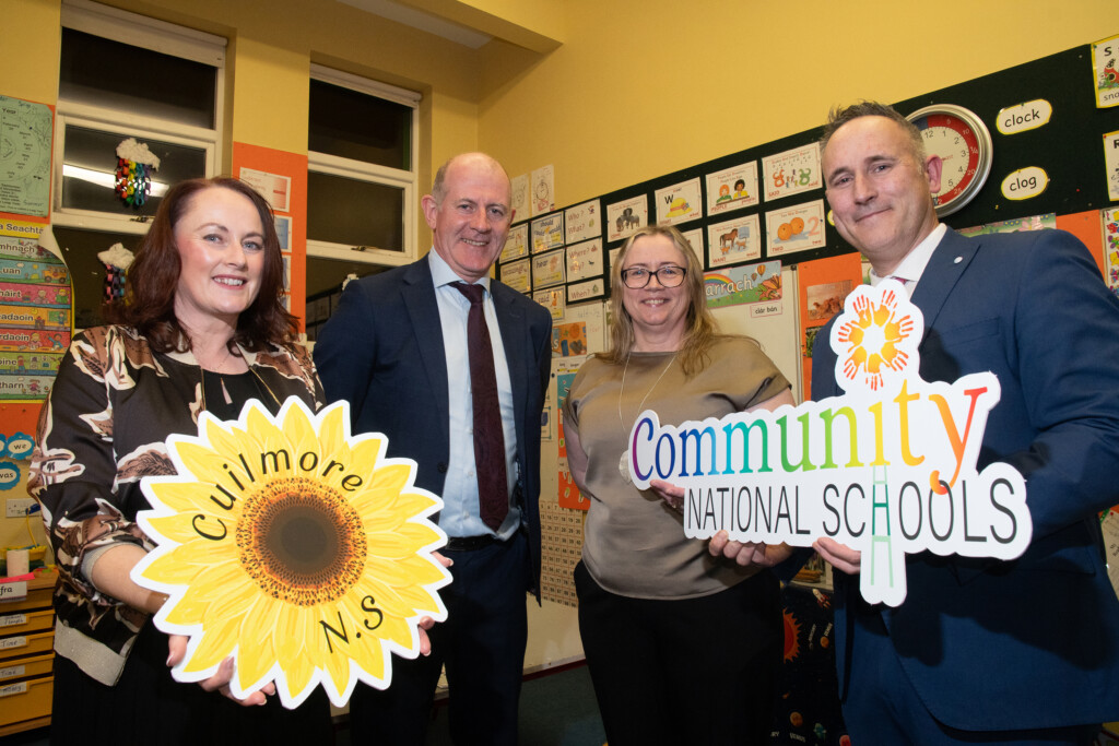2 women and 2 men in a classroom holding photo props of logos of Community National Schools and Cuilmore National School