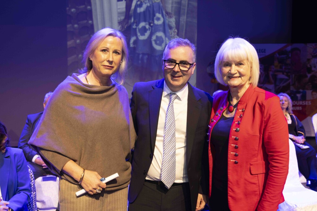 Sinead Graham, Sales Apprentice of the Year, standing with Peter Egan and Minister Harkin, all smiling and holding her award at the graduation event.