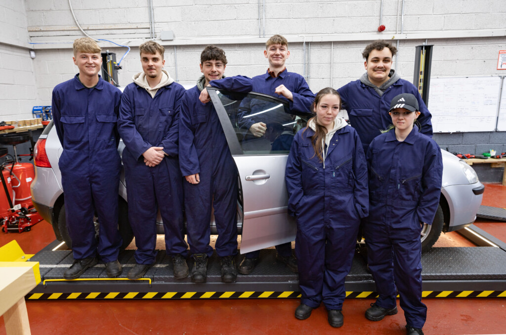 Left to right: Sligo CTC learners Jamie McNulty, Nicolas Hadi, Luke McGrath, Barry O’Hara, Aidan Barrett, Leah Conway, and Kayleigh Foy posing beside a car in the workshop