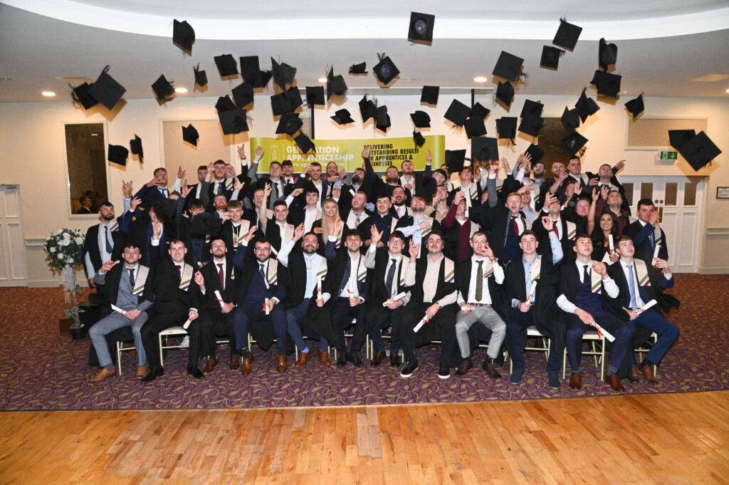 Group of people in graduation gowns throwing caps into the air.